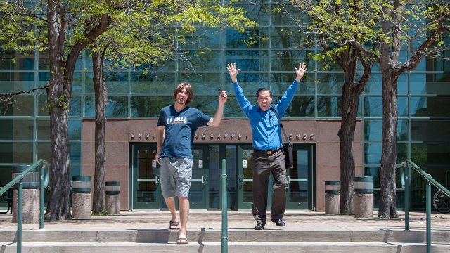 student and professor celebrating on the stepsof the EAS building